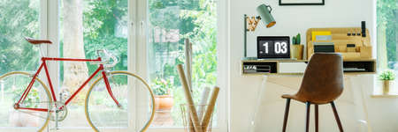 Red bike standing by the glass door in modern home office for freelancerの写真素材