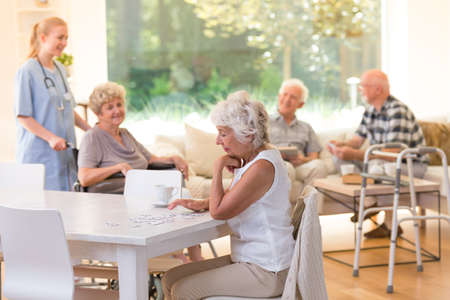 Senior woman doing puzzles at the table during her free time at the nursing houseの写真素材