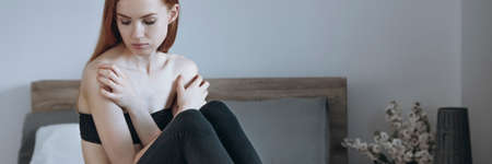 Panorama view of sad teenage girl with eating disorder sitting on bedの写真素材