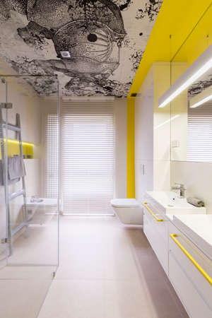 Abstract ink rhino painting on a ceiling of a stylish, modern bathroom with yellow tone paintの写真素材