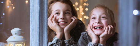 Happy kids waiting for christmas presents watching out of windowの写真素材