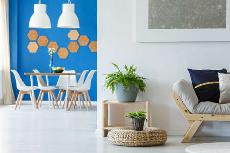 Creative arrangement of dining room with cork honeycombs on blue wall and white chairs at table