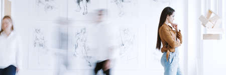 Art and people concept, young woman looking at wooden sculpture during exhibition in museum of modern artの写真素材