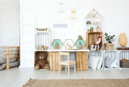 Plush toys and pillows on wooden handmade shelves in child's room with posters on wallの写真素材