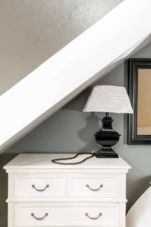Classic lamp on white cupboard in simple interior