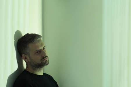 Nervous man leaning on wall with withdrawal symptoms at a hospital room