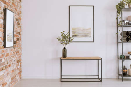Simple painting above wooden console table with twigs in a glass vase in modern living room interiorの写真素材