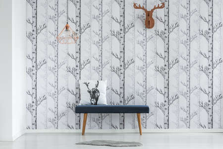Brown paper deer head hanging on the wall above dark blue bench with decorative cushion