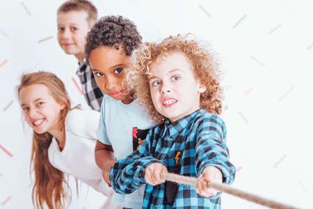 Kids pulling a rope together with all of their strengthの写真素材