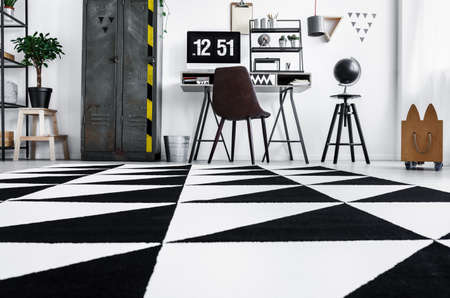 Low angle photo of home office with black and white carpet, old locker and desk with computerの写真素材