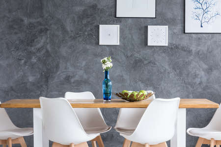 Apples in decorative bowl on wooden table in dining room with paintings on grey textured wallの写真素材