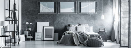 Black and white bedroom with pictures and pouf on the floor の写真素材