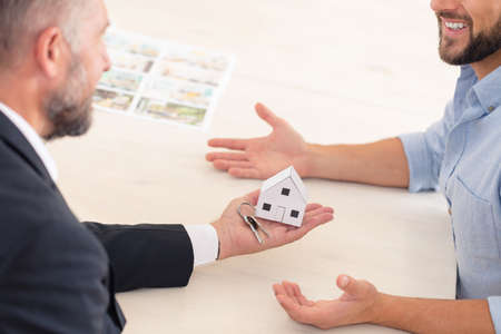Real estate agent giving a new owner apartment keys with house shaped keychainの写真素材