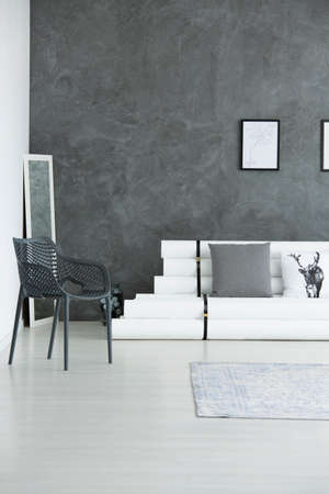 Modern living room design with black chair and white couch against gray concrete wallの写真素材