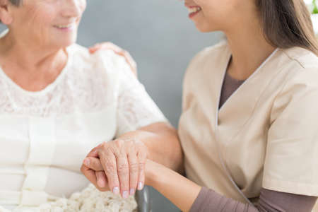 Close-up of happy family member holding hand of grandmother during meeting at homeの写真素材