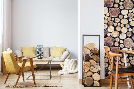 Beige sofa with yellow cushions and an armchair in a modern bright apartment decorated with wood motifsの写真素材