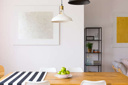 Surface of a wooden, dining table with a bowl of healthy apples, and a piece of fabric