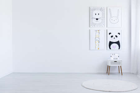 Copy space of white spacious autistic kid's room with drawings, white cabinet and carpetの写真素材