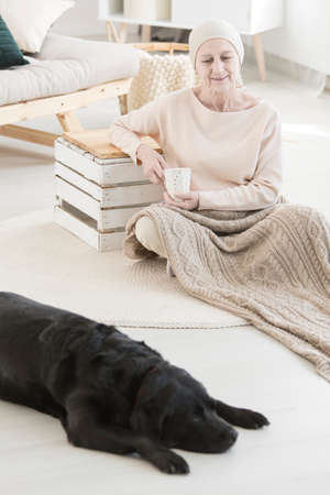Woman with cancer spending time with her faithful pupil while drinking teaの写真素材