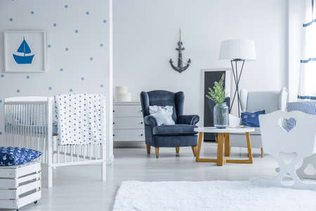 Navy blue armchair in spacious baby room in marine style with anchor on the wallの写真素材