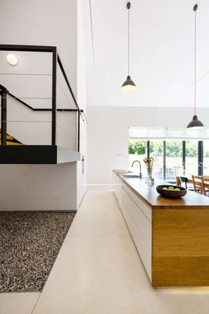 View of wooden kitchen island with sink and fragment of mezzanine floorの写真素材