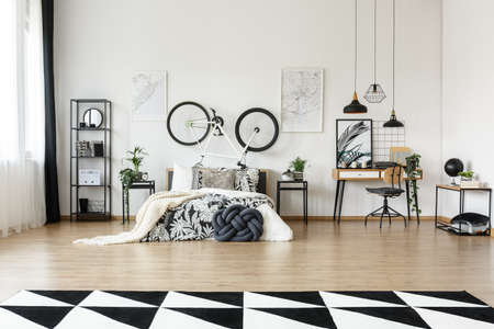 Dark knot pillow placed by a king-size bed with floral bedding in teenager's bedroomの写真素材