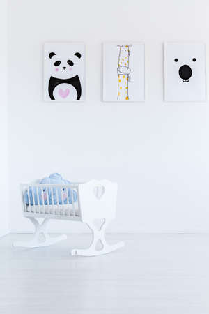 White cradle with blue cloud pillow in empty baby's room with animal pictures の写真素材