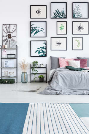 Bedroom with many posters with plants motif hanging on white wall