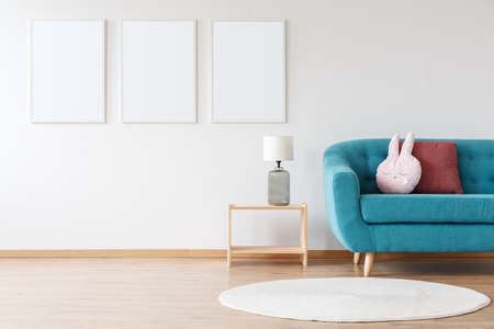 Mockup of white posters and lamp on wooden stool in child's room with blue sofa and white carpetの写真素材