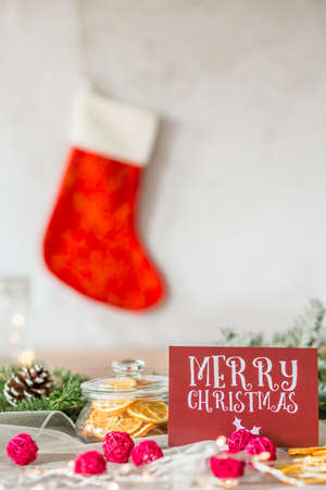 Red card with inscription merry christmas on a table with dried lemon slices in a jarの写真素材