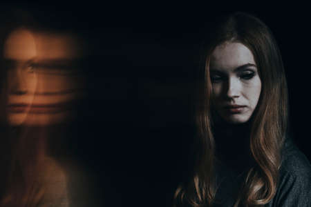 Young sad woman with split personality worrying about her conditionの写真素材