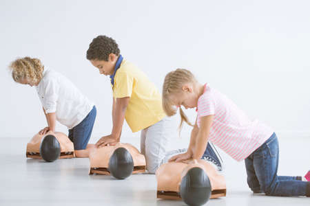 Kids doing resuscitation training on medical dummy during first aid course
