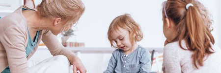 Friendly teacher listening to a shy kid during classes in nursery schoolの写真素材