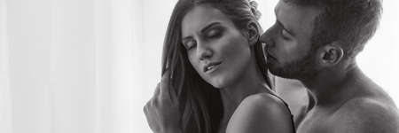 Affectionate naked couple is kissing during romantic foreplay in apartmentの写真素材