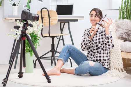 Young girl in checked shirt making curly hair tutorial on her video blogの写真素材