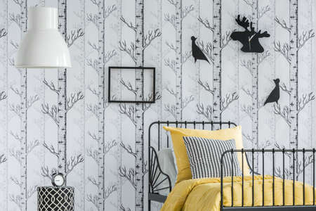 Big white lampshade and empty frame hanging on the wall in kid's room with forest motif