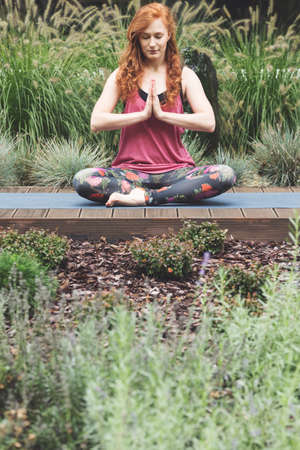 Caucasian woman meditating in the garden on a warm spring morningの写真素材