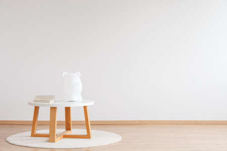 Wooden table with lamp and books on white rug against a wall with copy space in child's roomの写真素材