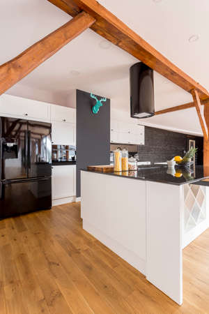 Black glossy fridge and blue decor on wall in spacious kitchen with white kitchenette and cabinets 