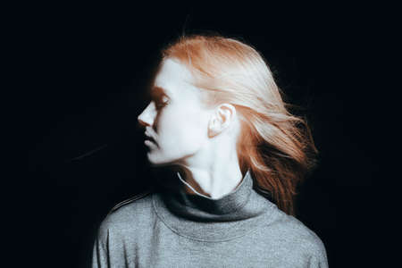 Photo of young female in bright light and on dark backgroundの写真素材