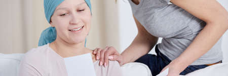 Woman spending time with younger sister with cancer wearing blue head headscarf