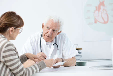 Elderly cardiologist consulting tests results with the patient after the infarctionの写真素材