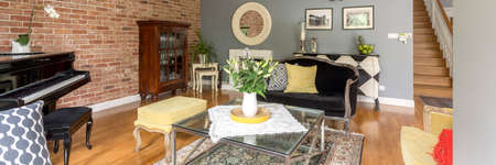 Artist's home with vintage living room with piano, black sofa and glass table