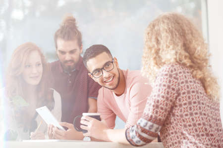 Group of friends talking and laughing during lunch break at the modern office