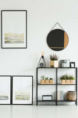 Round mirror above shelf with plants and gallery of paintings in bright living roomの写真素材
