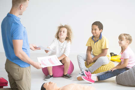 First aid instructor teaching children how to do resuscitation using phantom