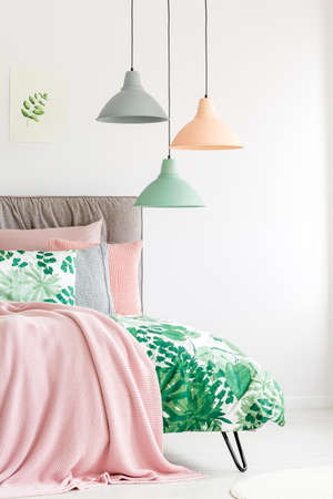 Pink pastel blanket and quilt with botanic print on bedの写真素材