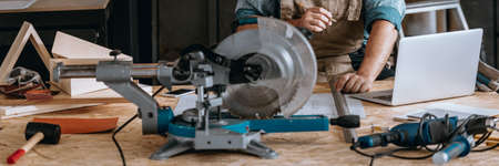 Carpenter doing complicated calculations using a laptop in his workshop