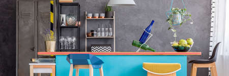 Glass bottles and lavender on blue kitchen island with designer bar stool against concrete wall