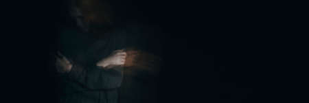 Victim of violence hidden in the black background with copy spaceの写真素材